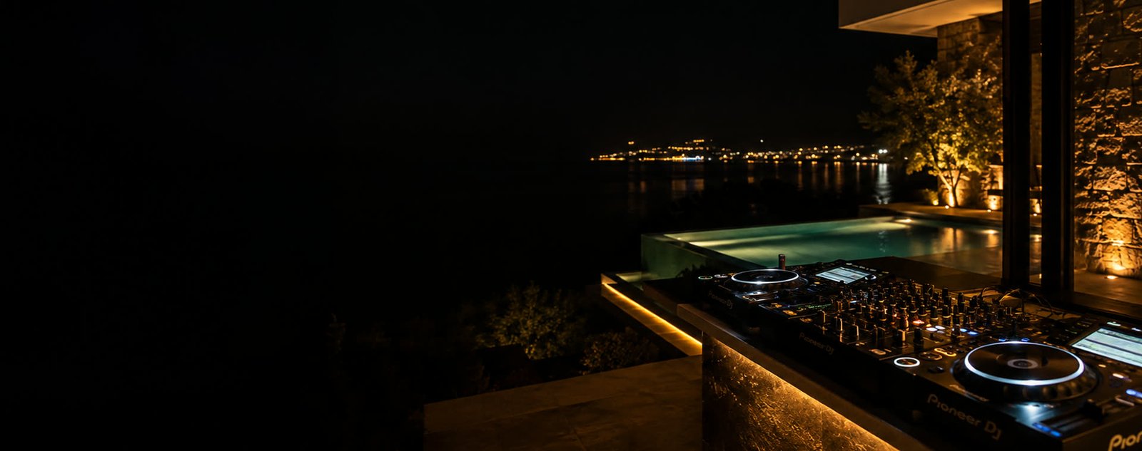 Bodrum'da özel bir villa terasında DJ kabini, gece, arkada sonsuzluk havuzu ve körfezin ışıkları
