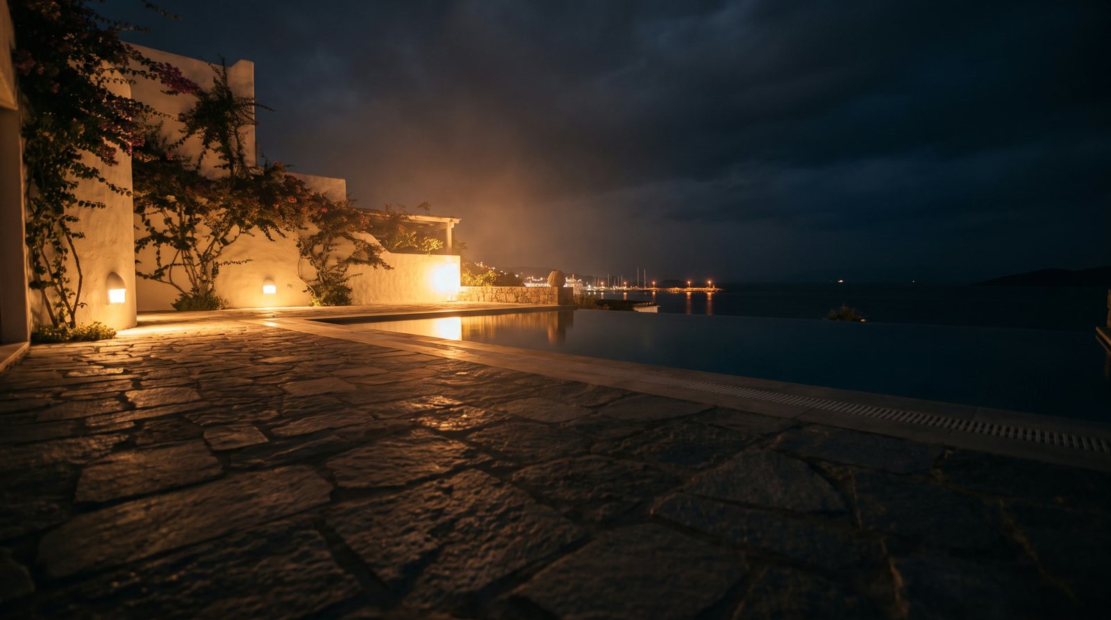 Bodrum'da bir villa terası, gece, sıcak ışıkla aydınlatılmış taş zemin ve arkada deniz